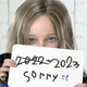The little girl character holds up a sign with the new release year 2023 and a message reading "sorry."